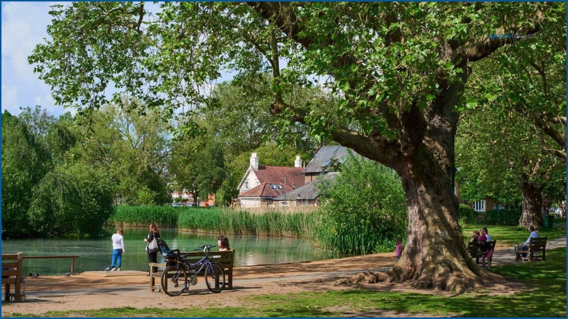 People relaxing in a park in London on a sunny day with a pond in late spring