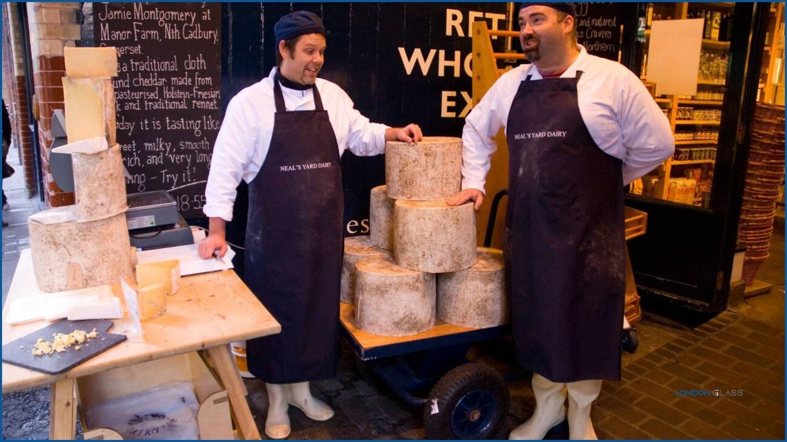 Cheese vendors at Neal’s Yard Dairy, Maltby Street Market displaying large cheese wheels