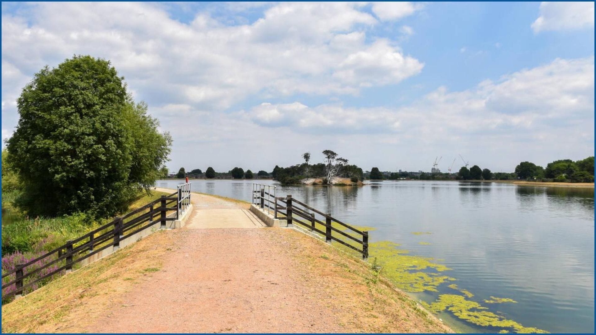 Walthamstow Wetlands reservoir with trees and sky reflection