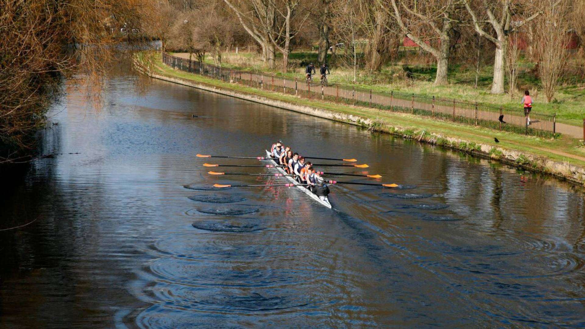 Rowers on the River Lee Navigation near Clapton Park, Hackney, surrounded by scenic greenery and pathways.