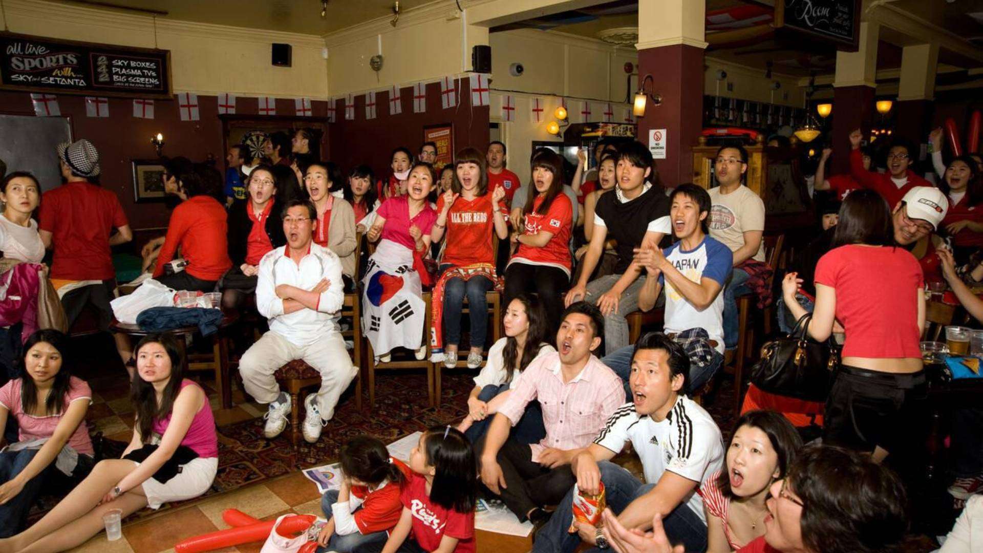 A group of Korean people watching a sports event in a pub in New Malden.