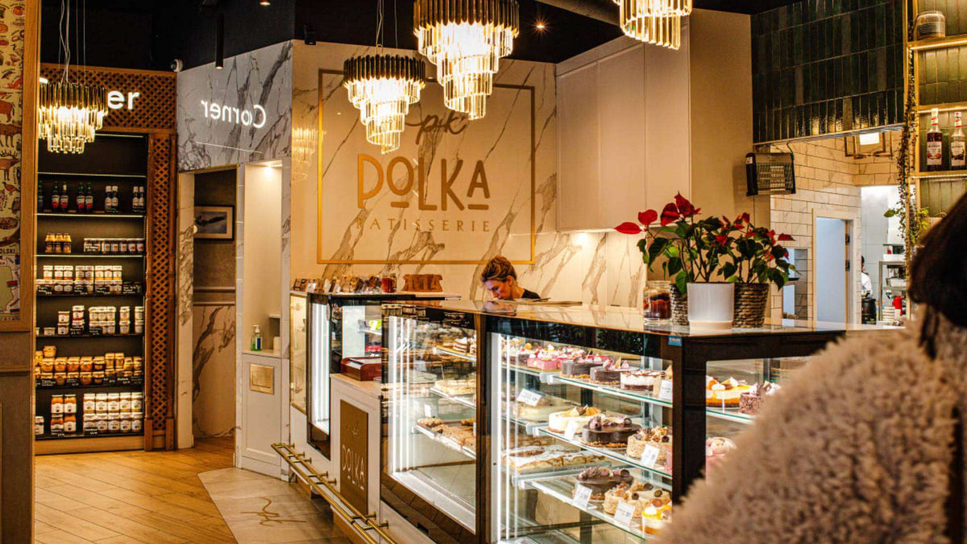 Interior view of Polka Kitchen with elegant decor, chandeliers, and a selection of desserts.