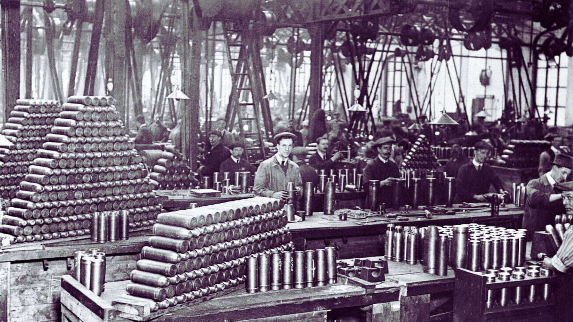 Historic factory interior during World War I, showcasing workers and munitions.