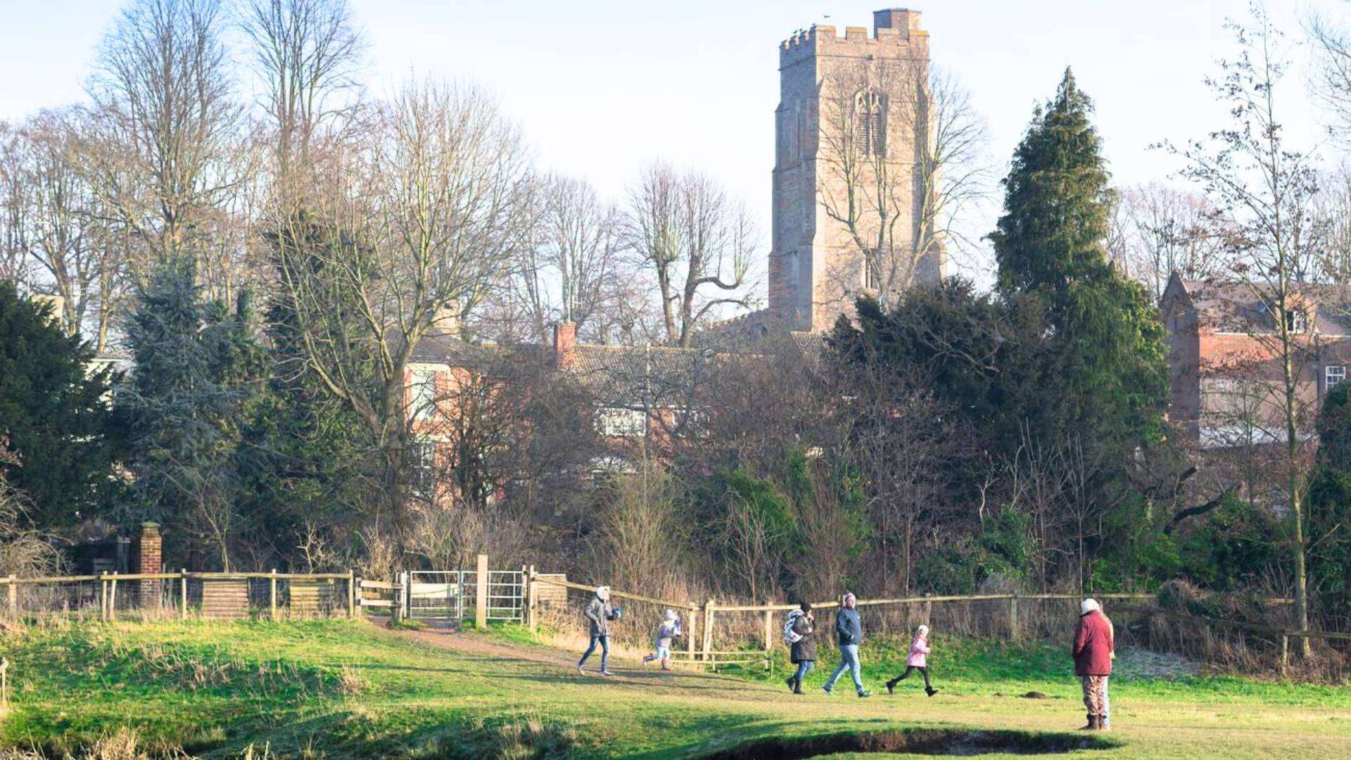 A family enjoying a hiking trail with a historic church in the background near Sudbury London.