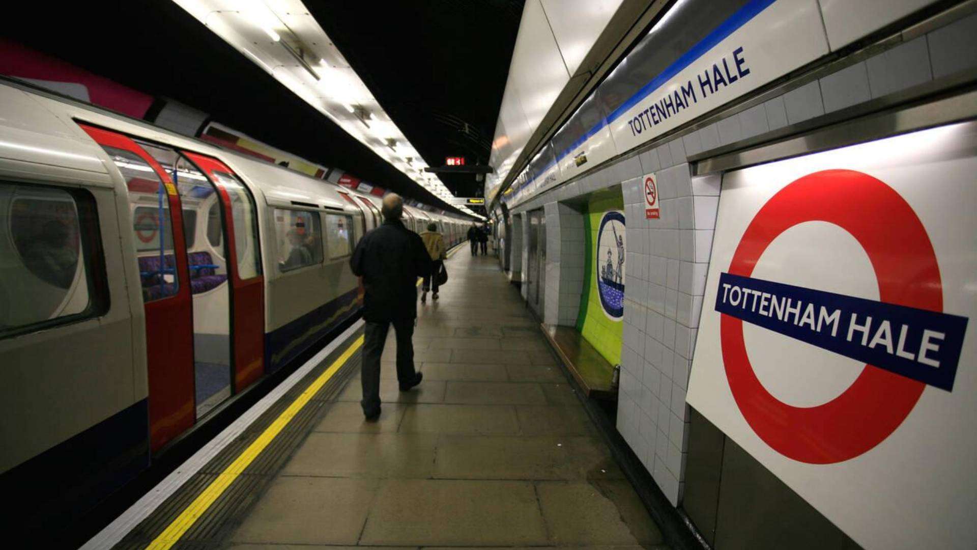 Tottenham Hale Underground Station platform with trains arriving and passengers walking.