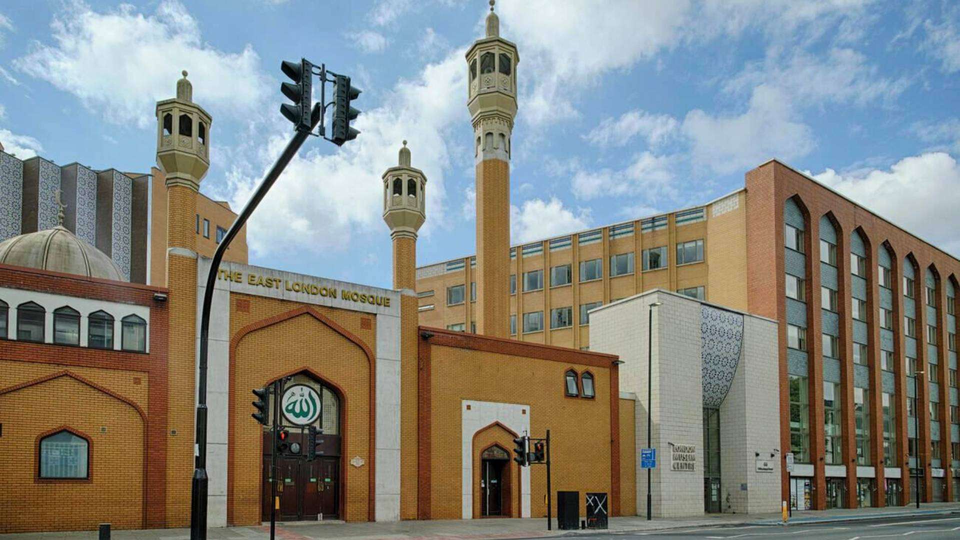 The East London Mosque, a stunning Islamic architectural landmark in Whitechapel, under a partly cloudy sky.