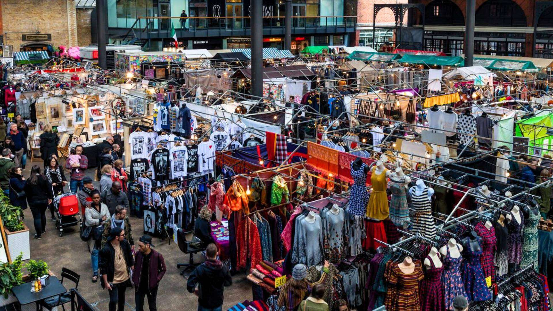 A busy scene inside Old Spitalfields Market in East London, featuring vintage clothing, handmade crafts, and independent stalls.